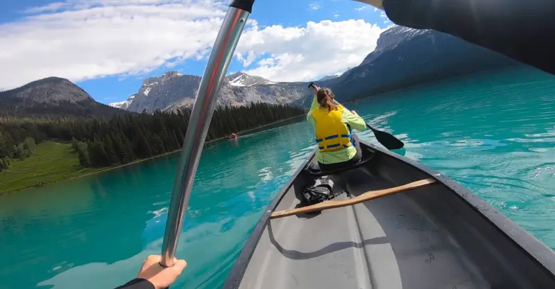Persona remando en canoa por las aguas turquesas de Emerald Lake con montañas nevadas al fondo, Yoho