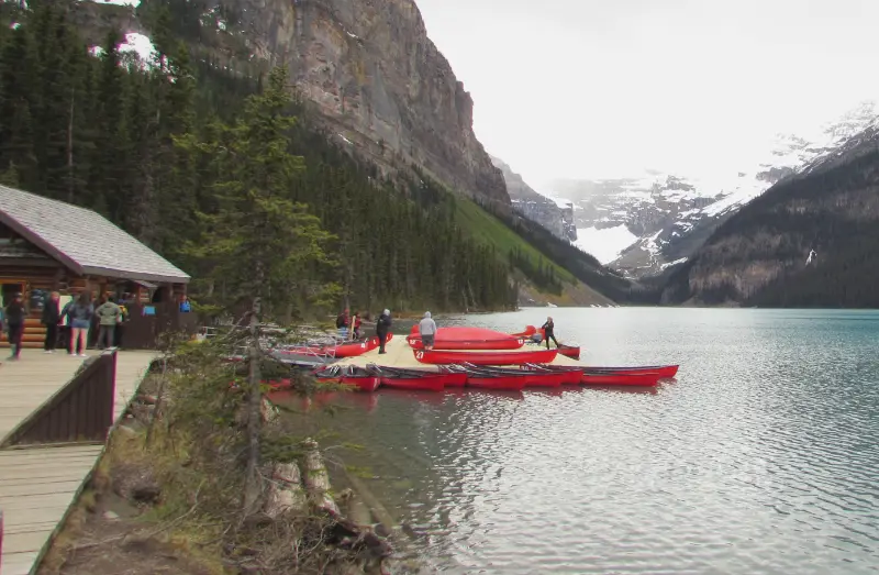 Canoas rojas amarradas en el embarcadero de madera de Lake Louise con las montañas nevadas al fondo.
