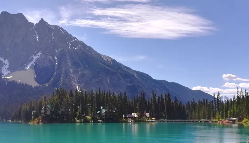 Vista de Emerald Lake desde la ruta que rodea el lago, con el lodge entre los pinos y una montaña rocosa al fondo