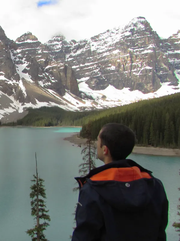 Viajero contemplando el lago Moraine y las montañas nevadas durante la subida por el sendero del mirador Rockpile.