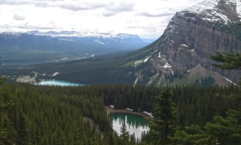 El lago Mirror Lake reflejando el Big Beehive bajo un cielo nublado en la ruta de senderismo hacia Lake Agnes.