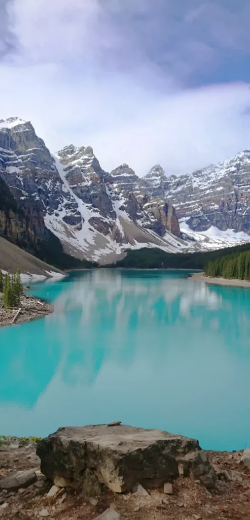 Vista vertical de Moraine Lake desde el mirador Rockpile, destacando el reflejo de las montañas nevadas en las aguas tranquilas y turquesas.