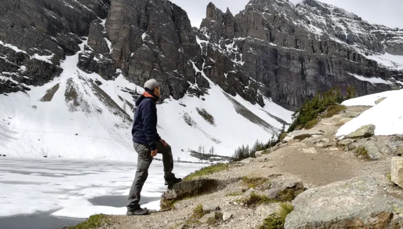 Senderista contemplando el Lake Agnes congelado y las montañas nevadas en el Parque Nacional Banff.