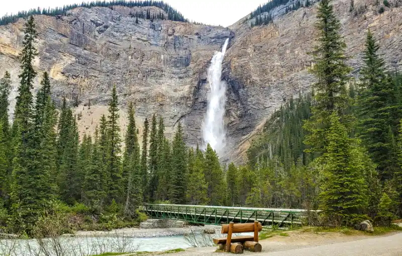 Puente de hierro verde sobre el río Yoho con Takakkaw Falls al fondo en Yoho National Park