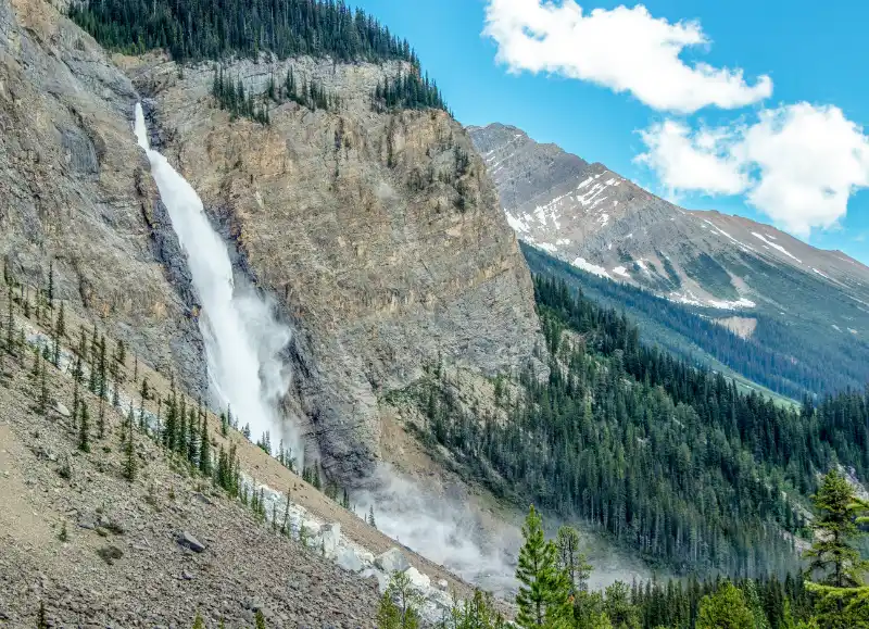 Vista lateral de Takakkaw Falls con las montañas del valle de Yoho al fondo en verano