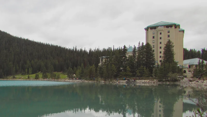 Fachada del hotel Fairmont Chateau Lake Louise y su reflejo en el agua turquesa visto desde el embarcadero de canoas.