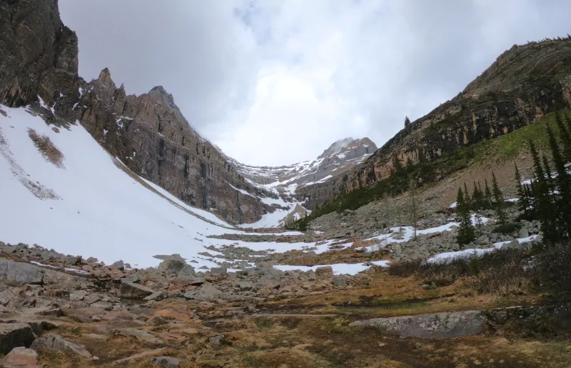 Valle rocoso con parches de nieve al final de Lake Agnes mirando hacia los picos circundantes en el Parque Nacional Banff.