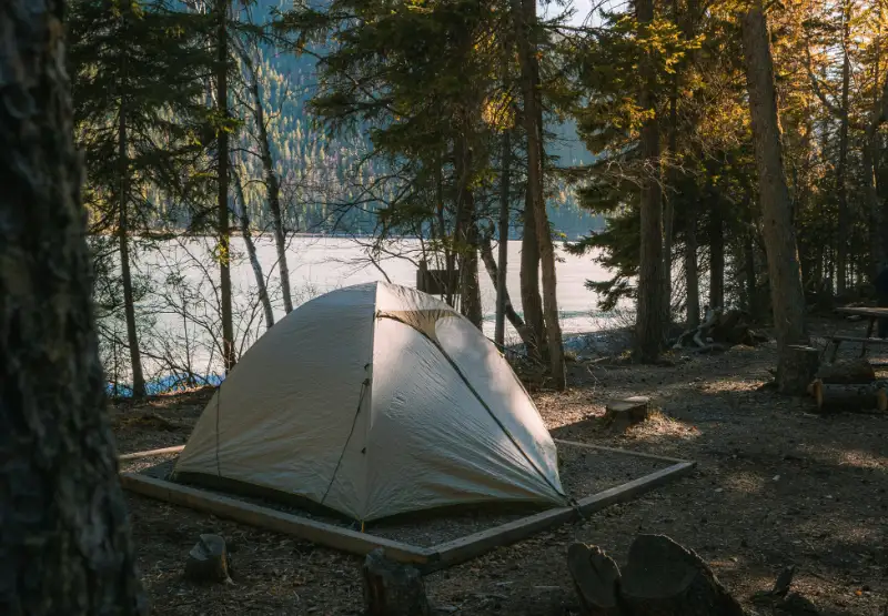 Zona de acampada backcountry en el Parque Nacional Yoho con tiendas de campaña cerca de un río y montañas nevadas al fondo.