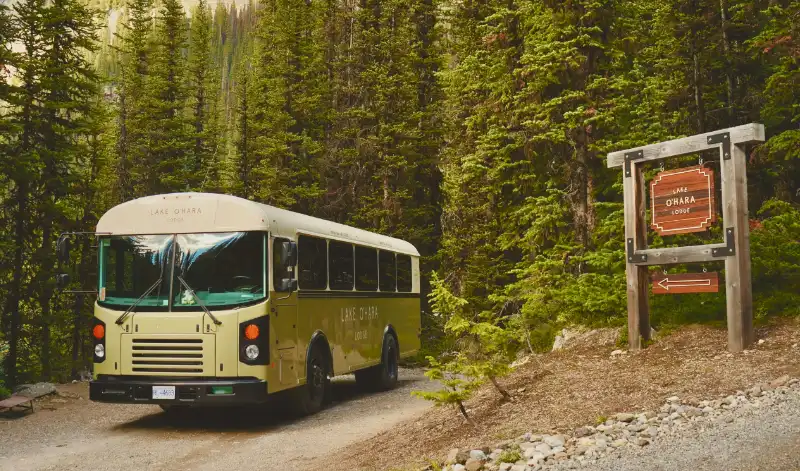 Autobús escolar amarillo modificado del Lake O'Hara Lodge aparcado cerca del inicio del sendero en el Parque Nacional Yoho.