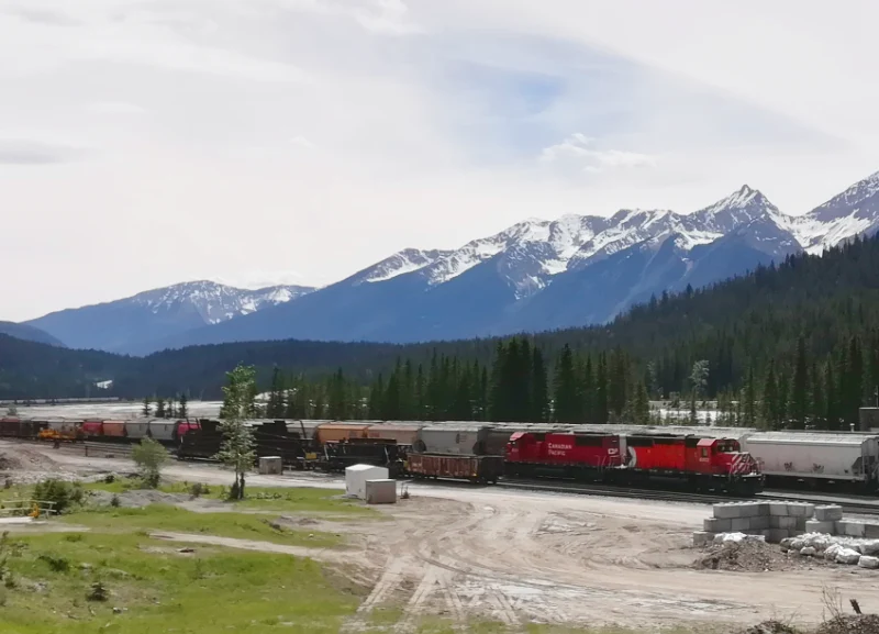 Tren de carga rojo de la Canadian Pacific Railway pasando por el pueblo de Field con las montañas nevadas del Parque Nacional Yoho al fondo.