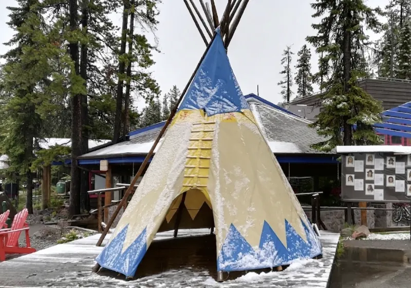 Tipi tradicional azul y amarillo cubierto de nieve junto al camino a Sunwapta Falls en el Parque Nacional Jasper.